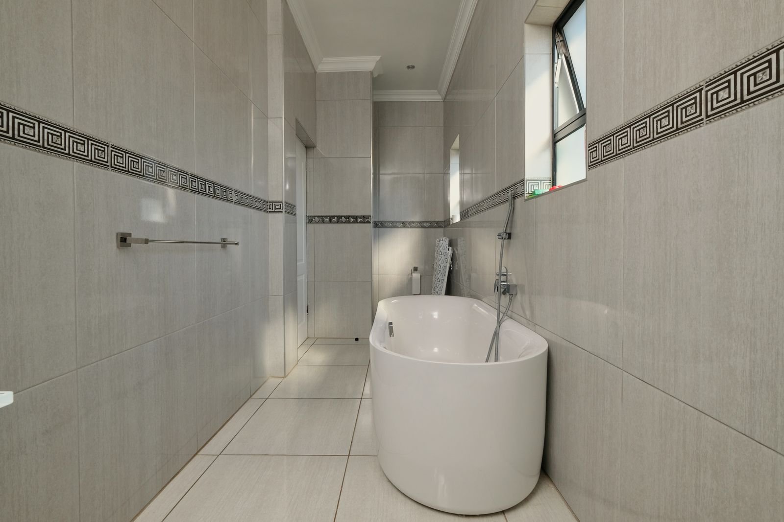 Bright tiled bathroom with a freestanding bathtub and natural light